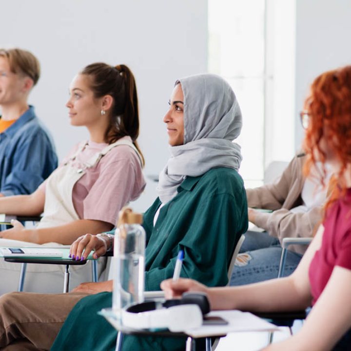 A group of university student sitting in classroom indoors, studying.