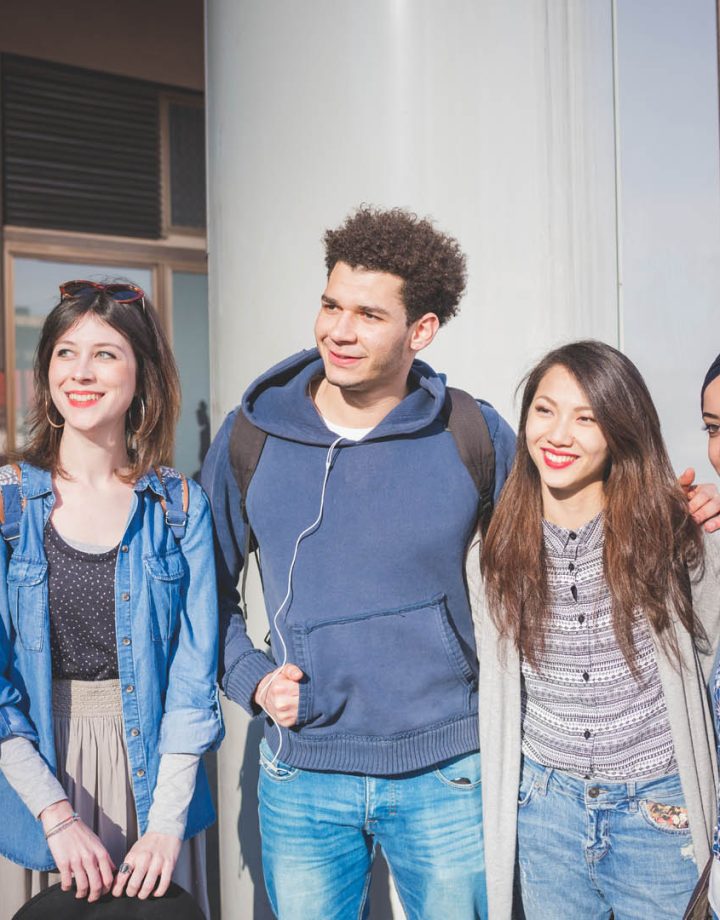 group of young friends posing and embracing in the street – relationship, diversity, new generation